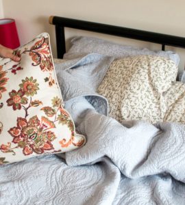 Gros plan sur les mains d'une femme faisant le lit dans une chambre