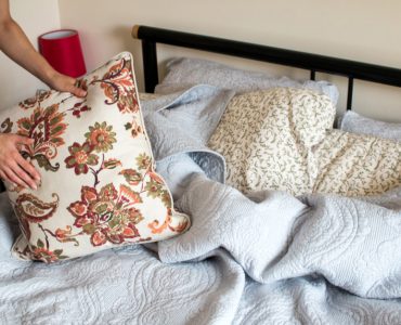 Gros plan sur les mains d'une femme faisant le lit dans une chambre