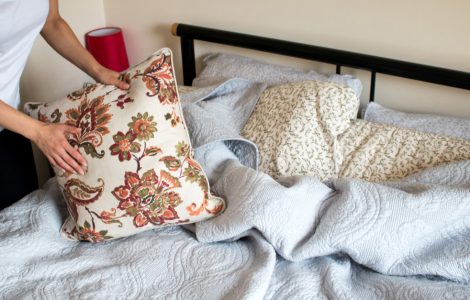 Gros plan sur les mains d'une femme faisant le lit dans une chambre