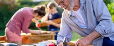 Un homme âgé, une femme et un enfant en train de bricoler à l'extérieur