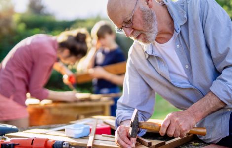Un homme âgé, une femme et un enfant en train de bricoler à l'extérieur
