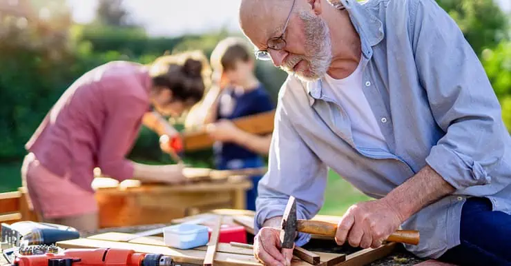 Un homme âgé, une femme et un enfant en train de bricoler à l'extérieur