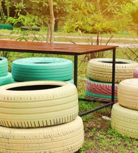 Des pneus colorés en guise de chaises de jardin autour d'une table en bois et en fer