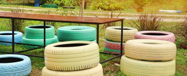 Des pneus colorés en guise de chaises de jardin autour d'une table en bois et en fer