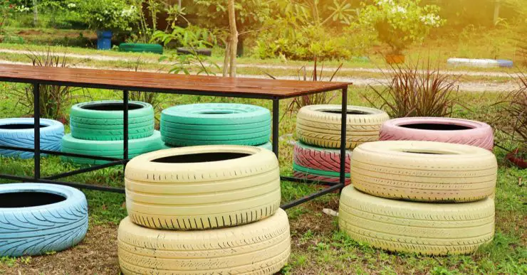 Des pneus colorés en guise de chaises de jardin autour d'une table en bois et en fer