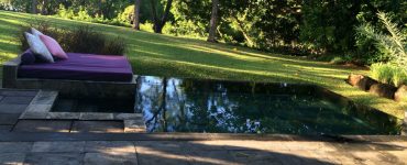 Un lit aménagé près d'une piscine naturelle dans le jardin