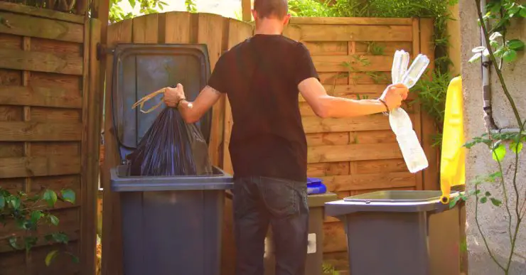 Un homme en train de déposer des déchets ménagers dans des bacs de recyclage différents