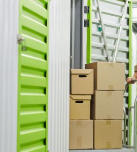 Un homme dans un entrepôt de stockage pousse un charriot rempli de carton