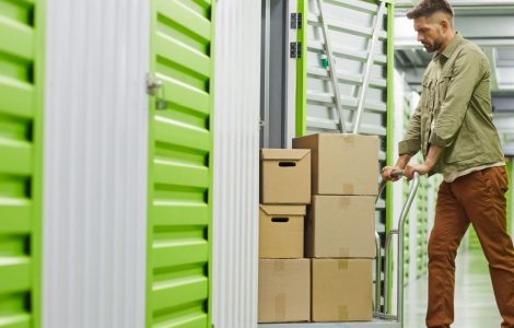 Un homme dans un entrepôt de stockage pousse un charriot rempli de carton