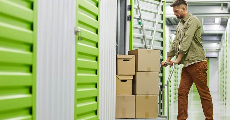 Un homme dans un entrepôt de stockage pousse un charriot rempli de carton