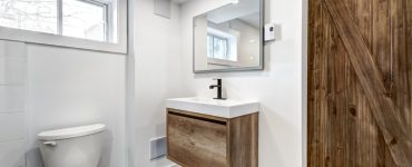 Une toilette avec une porte en bois et des fenêtres vitrées