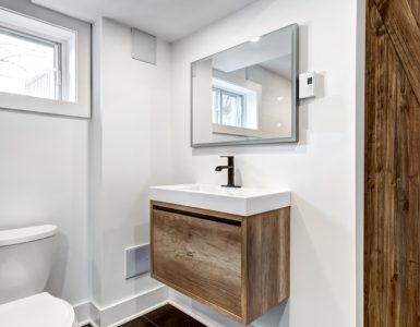 Une toilette avec une porte en bois et des fenêtres vitrées