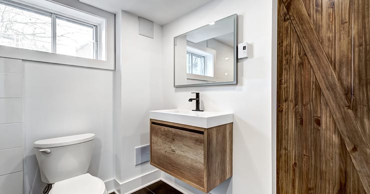 Une toilette avec une porte en bois et des fenêtres vitrées