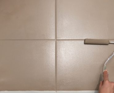 Zoom sur la main d'un homme peignant le carrelage mural en marron