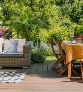Une table à manger et un salon sur une terrasse en bois dans un jardin verdoyant