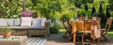 Une table à manger et un salon sur une terrasse en bois dans un jardin verdoyant