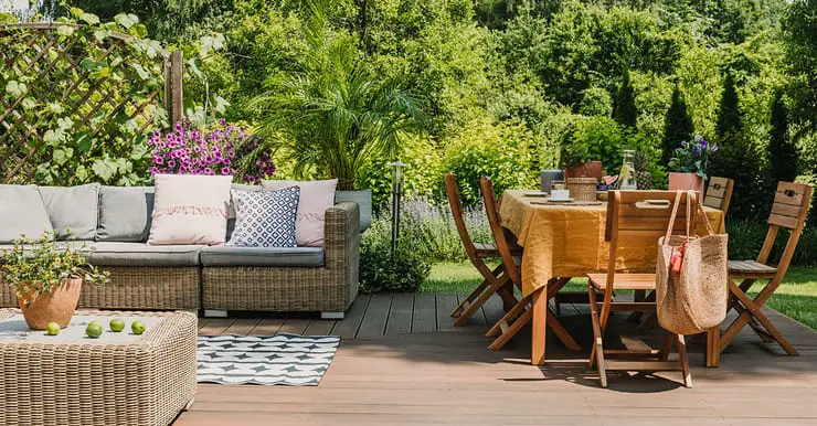 Une table à manger et un salon sur une terrasse en bois dans un jardin verdoyant