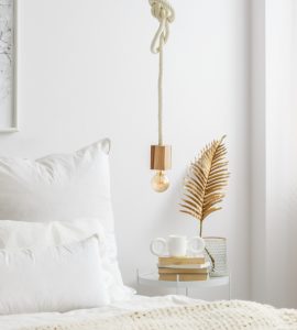 Lampe simple à ampoule suspendue par une corde au-dessus d'un lit blanc