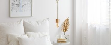 Lampe simple à ampoule suspendue par une corde au-dessus d'un lit blanc