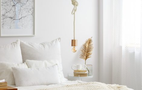 Lampe simple à ampoule suspendue par une corde au-dessus d'un lit blanc