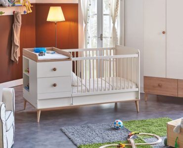 Une chambre de bébé avec un berceau, un tapis de jeu et une petite voiture en bois