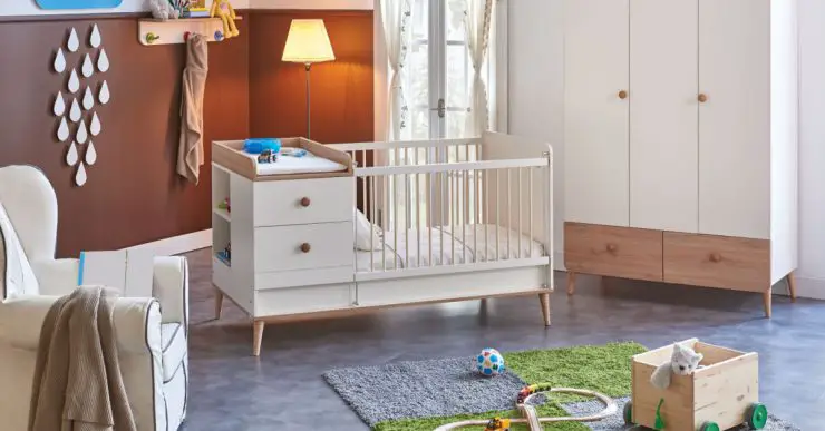 Une chambre de bébé avec un berceau, un tapis de jeu et une petite voiture en bois