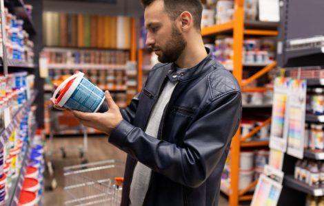 Un homme en blouson cuir noir choisissant une peinture dans une quincaillerie