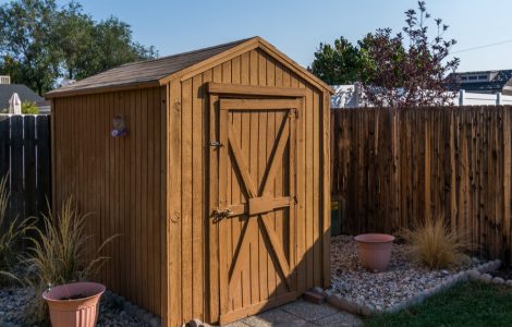 Un hangar à outils dans le jardin avec une clôture en bois