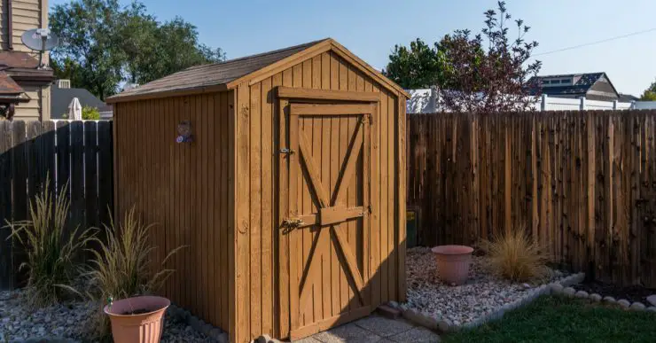 Un hangar à outils dans le jardin avec une clôture en bois