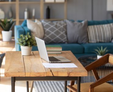 Un ordinateur portable posé sur une table de bureau en bois dans le salon