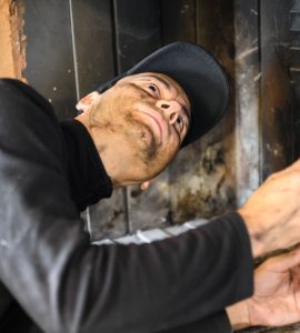 Un homme en casquette noire nettoie une cheminée
