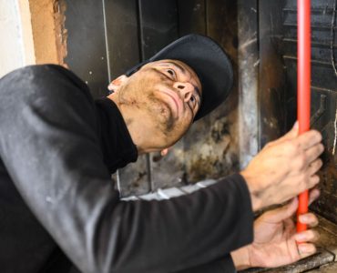 Un homme en casquette noire nettoie une cheminée