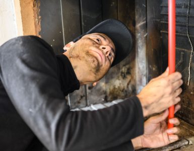 Un homme en casquette noire nettoie une cheminée