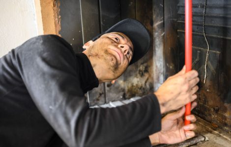 Un homme en casquette noire nettoie une cheminée