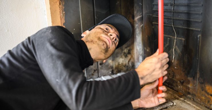 Un homme en casquette noire nettoie une cheminée