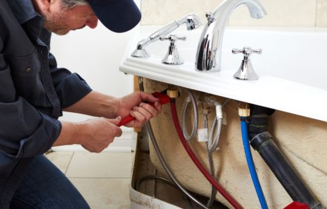 Un homme en casquette en train de fixer les tuyaux de plomberie