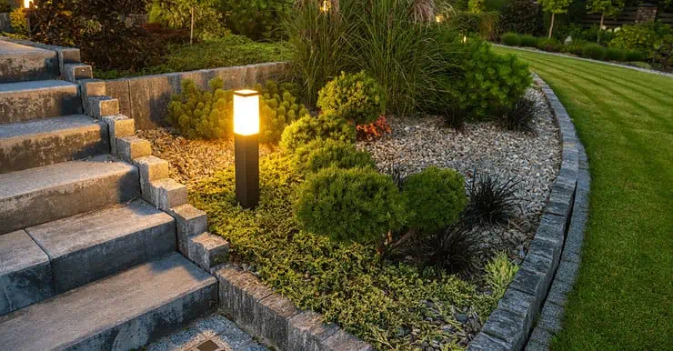 Une borne lumineuse LED éclairant l’escalier et le jardin à la tombée de la nuit