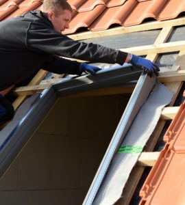 Un homme sur le toit installe une fenêtre velux