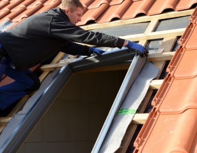 Un homme sur le toit installe une fenêtre velux