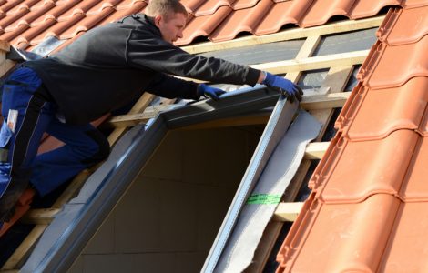 Un homme sur le toit installe une fenêtre velux