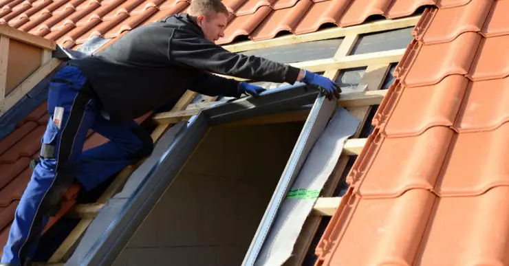 Un homme sur le toit installe une fenêtre velux