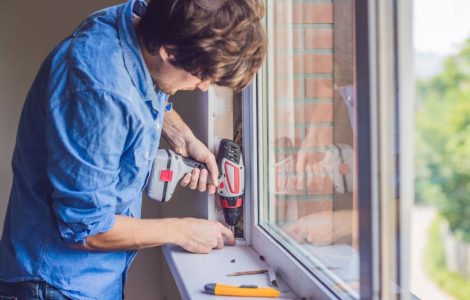 Un homme en chemise bleue installe une fenêtre vitrée