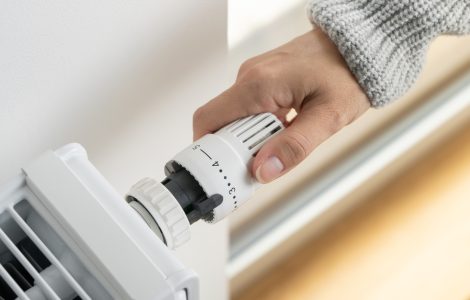Main d'une femme réglant le thermostat du radiateur dans sa maison