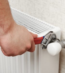 Main d'un homme resserrant le radiateur blanc