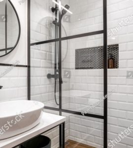 Une salle de bain noire et blanche avec un miroir rond