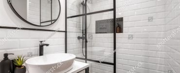 Une salle de bain noire et blanche avec un miroir rond