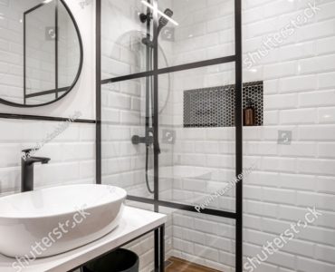 Une salle de bain noire et blanche avec un miroir rond