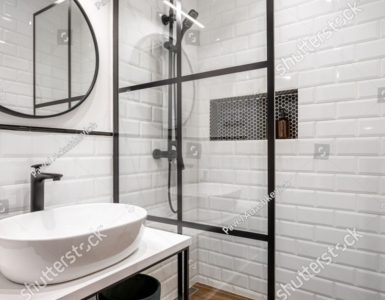 Une salle de bain noire et blanche avec un miroir rond