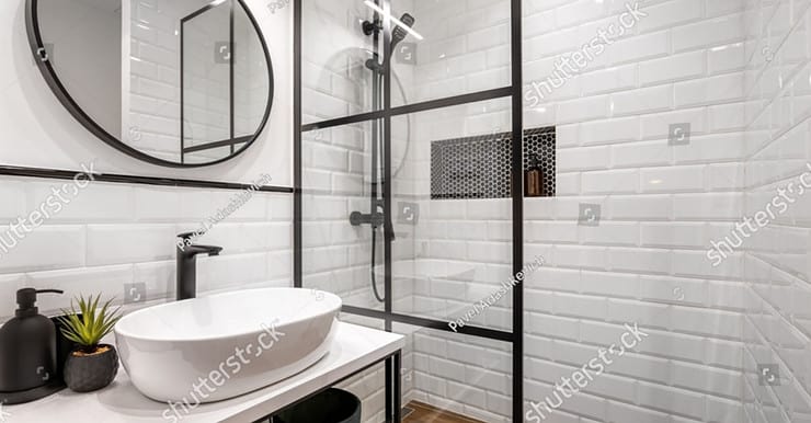 Une salle de bain noire et blanche avec un miroir rond