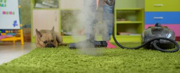 Une femme nettoie le tapis avec un nettoyeur vapeur dans la chambre des enfants